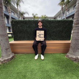 a man sitting on a wooden bench and holding a sign