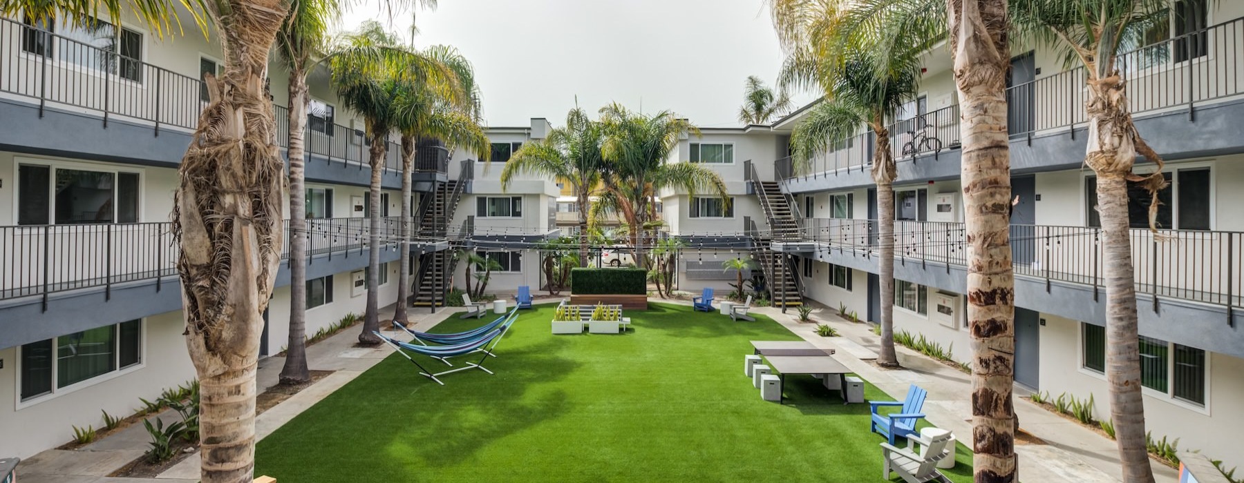 a courtyard with palm trees, tables and chairs