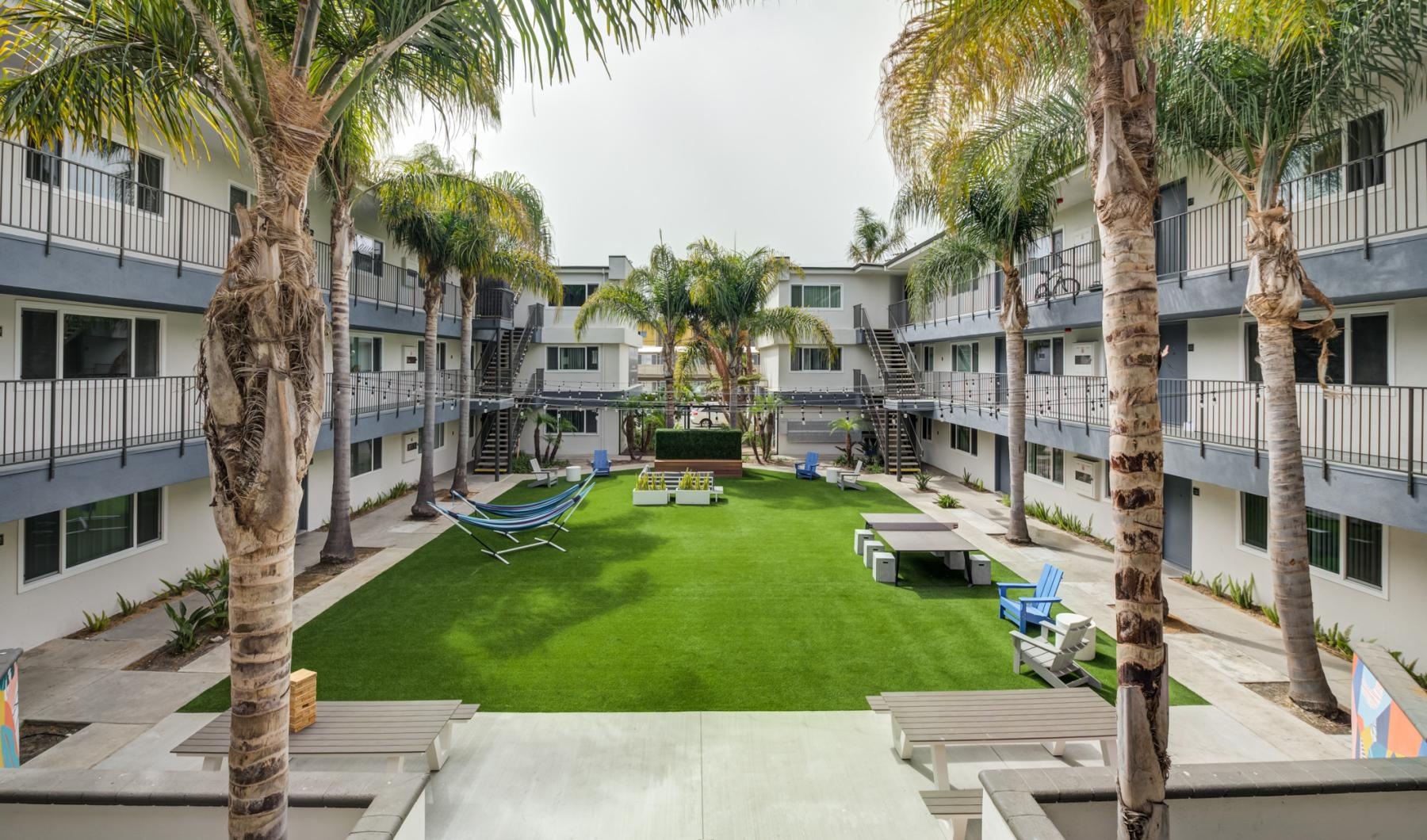 a courtyard with palm trees, tables and chairs